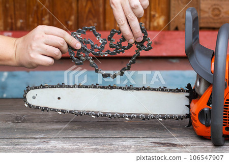 New chain for chainsaw. Setting up and replacing the chain on the chainsaw from the old to the new. Chain sharpening. Industry 106547907