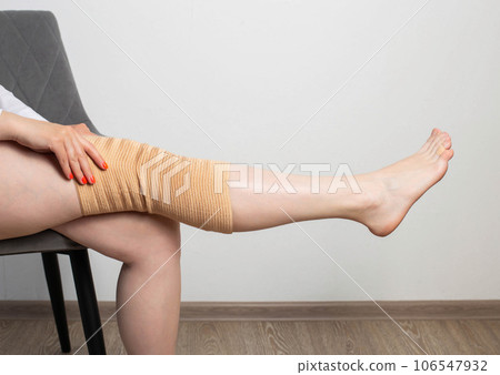 Orthopedic knee brace on a girl's leg. The concept of an elastic knee brace to support the knee joint after an injury. Copy space for text 106547932