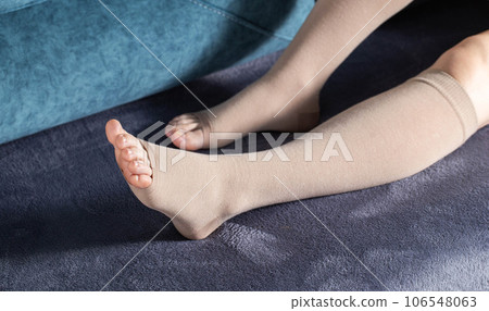 Girl's legs in compression stockings for varicose veins. Pregnancy and varicose veins Legs of a girl at home on the sofa. Pain and swelling in the legs. Girl's legs in compression stockings for varicose veins. Pregnancy and varicose veins Legs of a girl at home on the sofa. Pain and swelling in the legs. 106548063