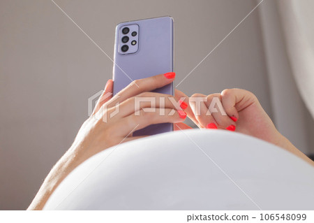 Pregnant girl with a mobile phone in her hands against the background of a large belly. Enjoying technology 106548099