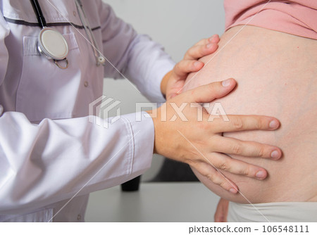The doctor feels the big belly of a pregnant girl, close-up. Consultation with a gynecologist. 106548111