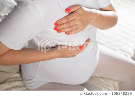 Pregnant girl holds on to the mammary gland. The concept of swelling and increase in the size of the female breast during pregnancy. Pain, close-up 106548229