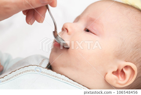 A mother from a spoon gives soothing drops to a child for a good sleep, close-up. 106548456