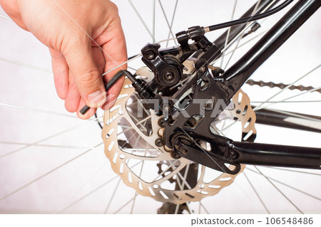 Unscrewing the bicycle brake caliper to change the brake pads and adjust the brakes. Copy space for text Unscrewing the bicycle brake caliper to change the brake pads and adjust the brakes. Copy space for text 106548486