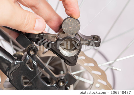 new brake pads in hand on the background of a bicycle brake caliper. Replacement of brake pads, close-up 106548487