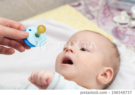 Little caucasian baby boy and pacifier. The habit of the sucking reflex in infants. Little caucasian baby boy and pacifier. The habit of the sucking reflex in infants. 106548737