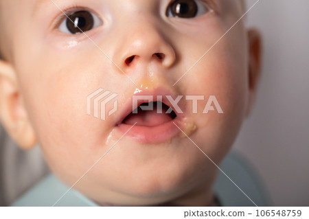 Portrait of a 9 month old baby with a dirty mouth after eating. The concept of feeding babies after breast milk. Close-up 106548759