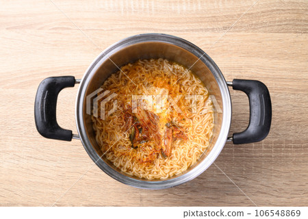 Korean spicy instant noodles soup with kimchi and egg in hot pot on wooden background, Table top view 106548869
