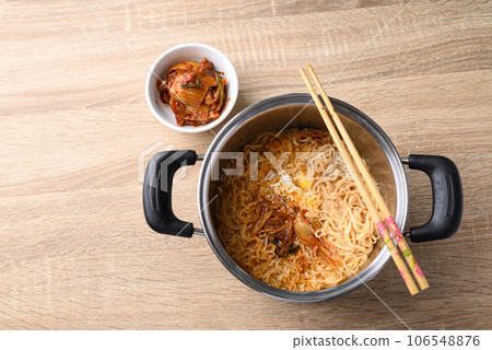 Korean spicy instant noodles soup with kimchi and egg in hot pot on wooden background, Table top view Korean spicy instant noodles soup with kimchi and egg in hot pot on wooden background, Table top view 106548876