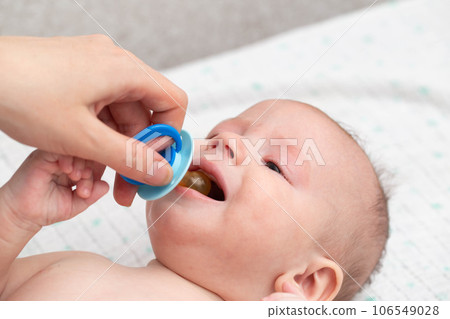 Little baby boy crying with a pacifier in his mouth. The concept of weaning the habit of sucking a pacifier in children, close-up. Copy space for text Little baby boy crying with a pacifier in his mouth. The concept of weaning the habit of sucking a pacifier in children, close-up. Copy space for text 106549028