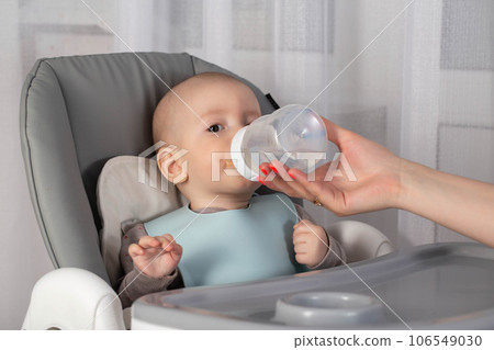 A mother feeds a baby with a milk formula with bifidobacteria from a bottle. Feeding children. 106549030