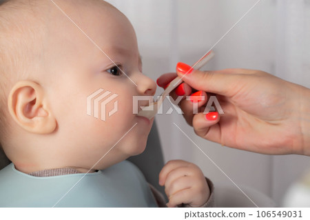 The first feeding with fruit puree for a baby boy who is 6 months old, close-up. Copy space for text 106549031