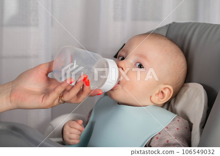 A mother feeds a baby with a milk formula with bifidobacteria from a bottle. Feeding children. 106549032
