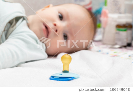 Little caucasian boy baby and dummy. Orthodontic pacifier for children. Formation of bite in children, close-up Little caucasian boy baby and dummy. Orthodontic pacifier for children. Formation of bite in children, close-up 106549048