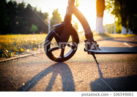 Scooter wheel on the background of a sunset in summer, close-up. Scooter rental business concept. Self-sharing. 106549061