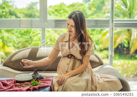 A serene moment captured as a pregnant woman after 40 embraces the soothing benefits of aroma oils and an aroma diffuser, enhancing her pregnancy journey with relaxation and tranquility 106549281