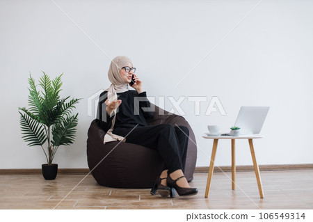 Entrepreneur in beanbag speaking on cell phone in workplace 106549314