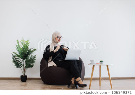 Professional hosting web conference via laptop in pouf chair 106549371