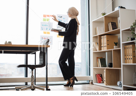 Businesswoman with laptop viewing data visuals on glass Businesswoman with laptop viewing data visuals on glass 106549405