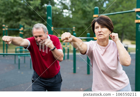 Sports pensioners are engaged in martial art on the sports ground in open air Sports pensioners are engaged in martial art on the sports ground in open air 106550211