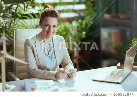 smiling business woman in light business suit in green office smiling business woman in light business suit in green office 106551074