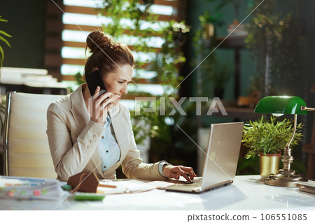 smiling woman worker in green office talking on phone 106551085