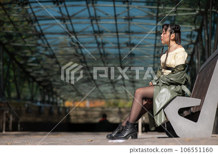 A young Asian woman sits on a bench at the subway exit. A young Asian woman sits on a bench at the subway exit. 106551160
