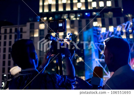Camera man recording while organizing scene with interviewer at night event Camera man recording while organizing scene with interviewer at night event 106551693