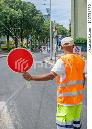 Construction worker holding a Red Stop Sign and directing traffic on the street Construction worker holding a Red Stop Sign and directing traffic on the street 106551780