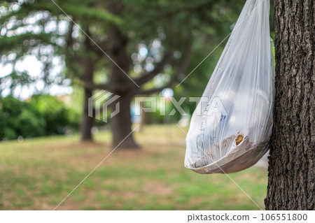 Garbage bag hung on tree in nature showing human polluting impact in green areas 106551800
