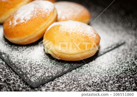German Krapfen with drizzling glazed sprinkles in black elegant background 106551860