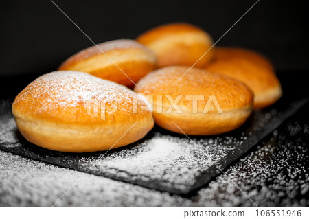 German Krapfen with drizzling glazed sprinkles in black elegant background 106551946