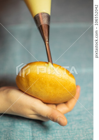 Hand filling Krapfen with Vanilla Cream. Dessert from Germany like donuts dough 106552042