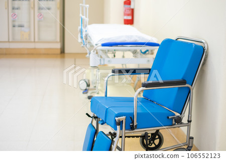 Specialized blue padded Wheelchair with Hospital stretcher in corridor background Specialized blue padded Wheelchair with Hospital stretcher in corridor background 106552123