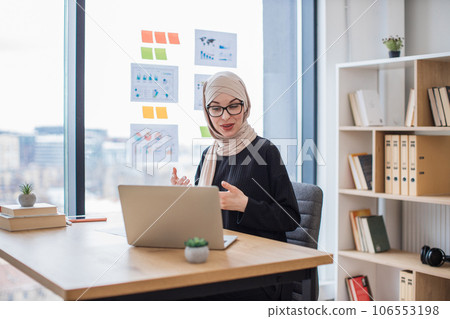Arabian lady hosting web conference via laptop in workplace Arabian lady hosting web conference via laptop in workplace 106553198
