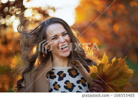 smiling young female in beige coat and orange hat 106553485