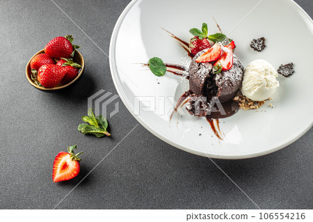 Chocolate fondant lava cake with strawberries, traditional french chocolate cake with liquid filling Chocolate fondant lava cake with strawberries, traditional french chocolate cake with liquid filling 106554216