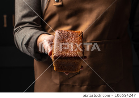 Small brown bread in hands, domestic cozy bakery pastry. Healthy food concept. place for text 106554247