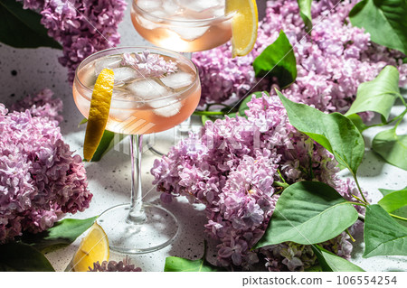 Rose wine in glass and lilac flowers over white background, Summer celebration, wedding greeting card, invitation concept Rose wine in glass and lilac flowers over white background, Summer celebration, wedding greeting card, invitation concept 106554254