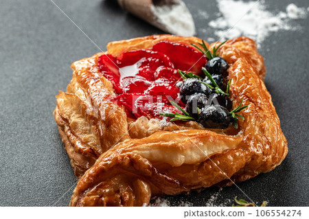 Small open pie made of puff pastry with fresh berries on a dark background, Food recipe background. Close up 106554274