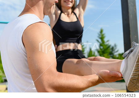 Woman are doing the exercise L-sit and hanging on the horizontal bar 106554323