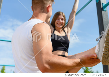 Woman are doing the exercise L-sit and hanging on the horizontal bar 106554324