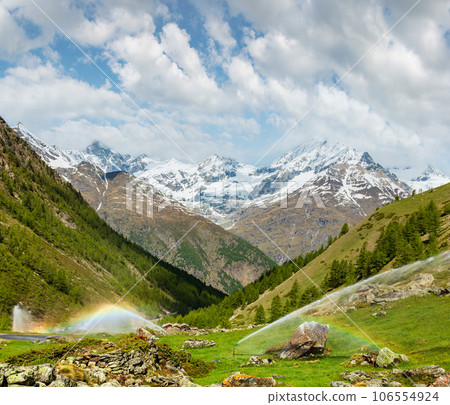 Rainbows in irrigation water spouts in Alps mountain Rainbows in irrigation water spouts in Alps mountain 106554924