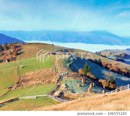 Autumn misty morning plateau with stack of hay and country dirty road (Mighgirya village outskirts, Carpathian Mountains, Ukraine). Autumn misty morning plateau with stack of hay and country dirty road (Mighgirya village outskirts, Carpathian Mountains, Ukraine). 106555285