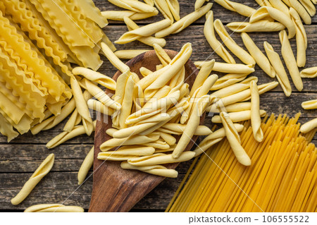 Fusilli pugliesi. Italian twisted pasta and spaghetti on wooden table. Top view. Fusilli pugliesi. Italian twisted pasta and spaghetti on wooden table. Top view. 106555522