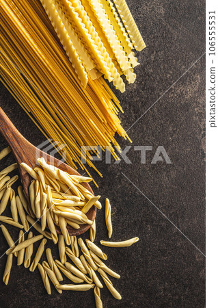 Fusilli pugliesi. Italian twisted pasta and spaghetti on black table. Top view. Fusilli pugliesi. Italian twisted pasta and spaghetti on black table. Top view. 106555531