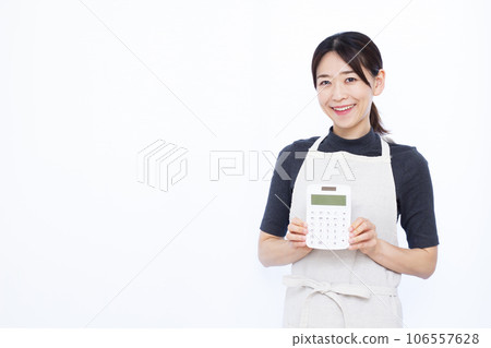A housewife in her thirties with a calculator in front of a white background 106557628