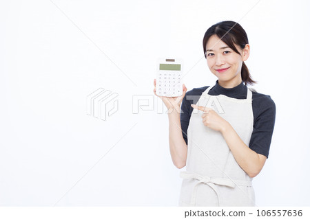 A housewife in her 30s pointing at a calculator in front of her white teeth A housewife in her 30s pointing at a calculator in front of her white teeth 106557636