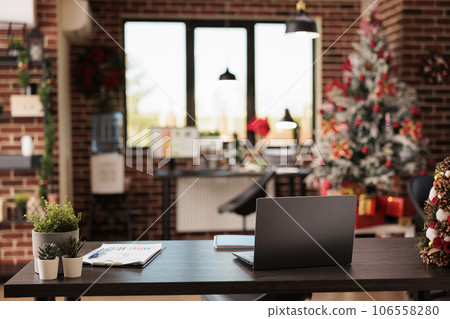 Laptop on desk at festive decorated corporate office workplace with christmas tree. Computer on table at company workspace during new year holiday winter season with no people 106558280