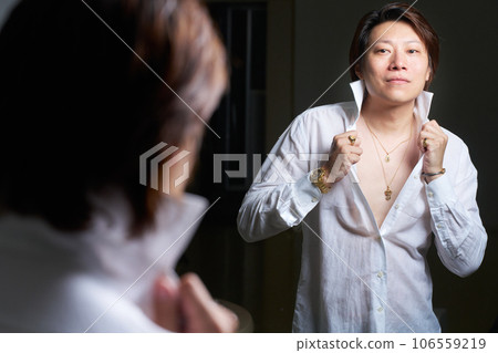 一個熱愛配飾的男人在鏡子前準備。男士珠寶時尚形象。 106559219